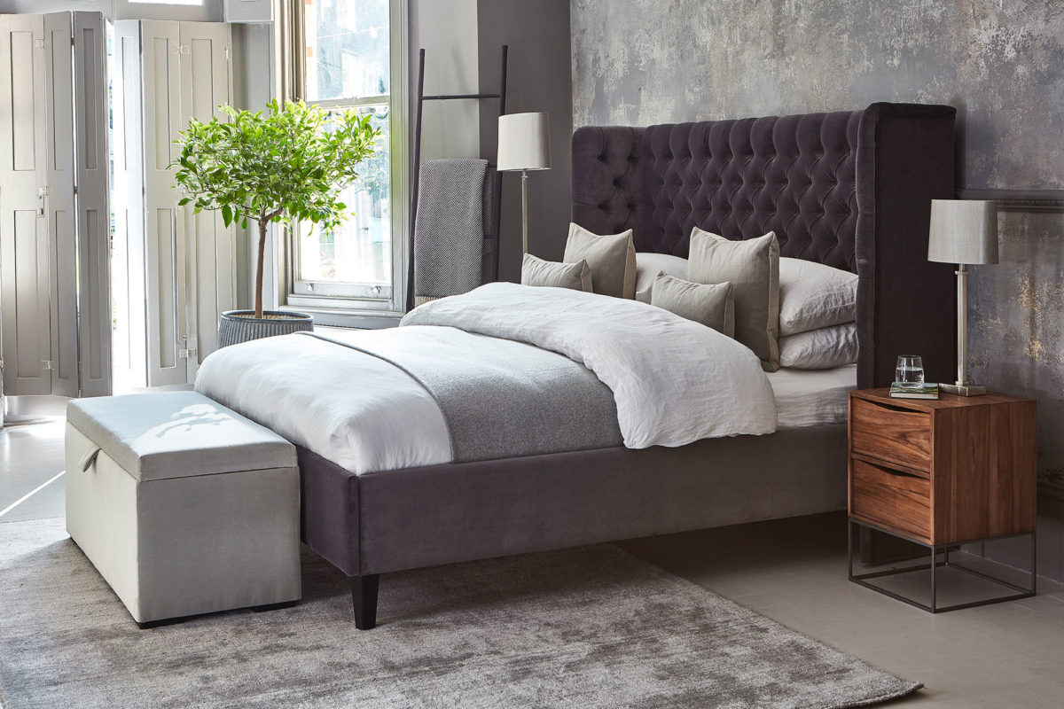Upholstered montclair bed from Raft with soft upholstered ottoman, bedside table and table lamp